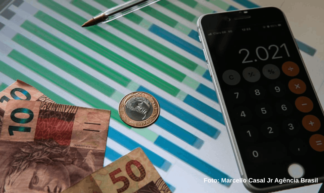 Dinheiro brasileiro, calculadora de um iphone em cima de um papel gráficos. Inflação oficial fica em 0,12% em julho, diz IBGE